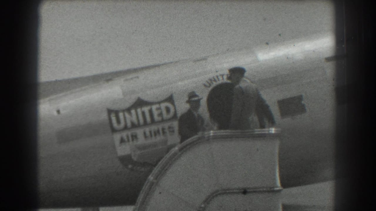 Two people stand near exterior stairs beside the United Air Lines fuselage.
