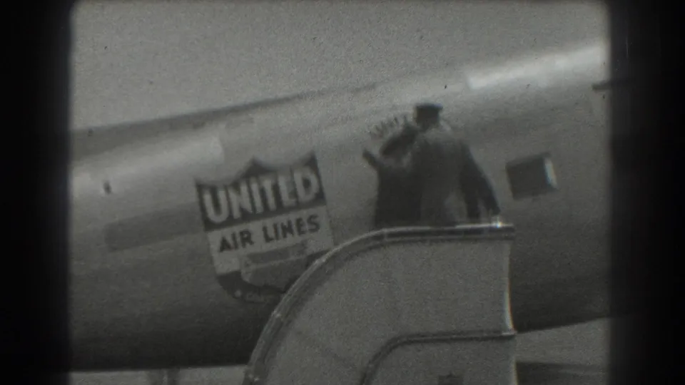 1939 San Francisco home-movie frame showing a figure raising an arm at the stairs by a United Air Lines plane.