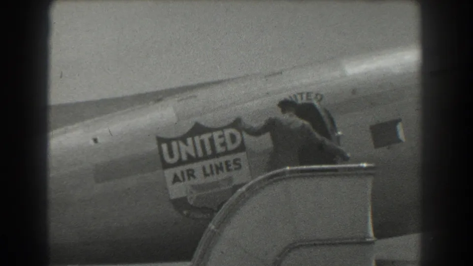 In 1939 San Francisco footage, a suited man in a hat exits beside the United Air Lines logo on an aircraft fuselage.