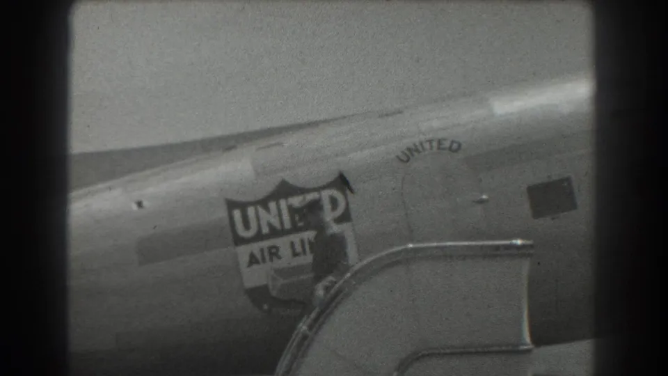 The aircraft side fills the frame, showing the United Air Lines shield logo and stairs as the passenger moves out of view.