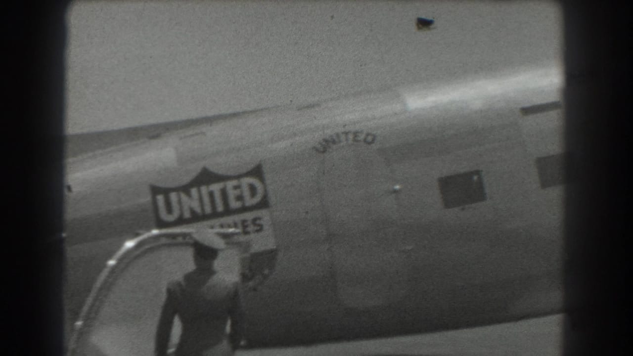 Ground crew member walking near a United Air Lines aircraft and stairs.