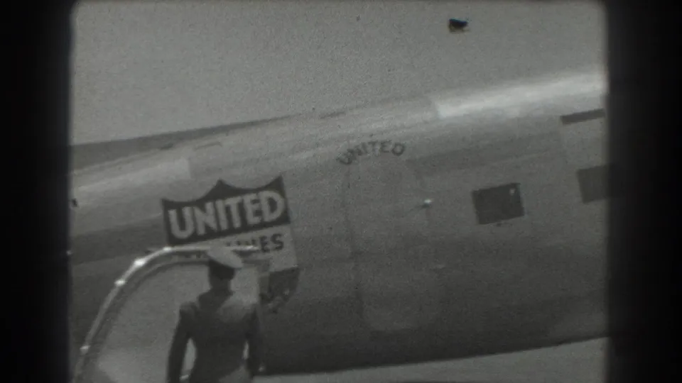 1939 San Francisco frame with a uniformed ground crew member near passenger stairs and the United Air Lines logo on the fuselage.