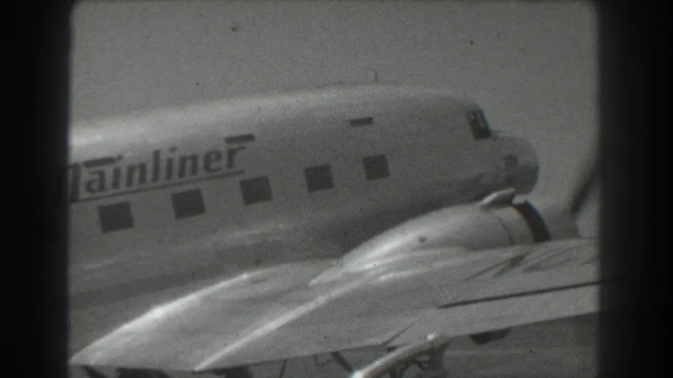 1939 San Francisco frame of The Mainliner aircraft with fuselage windows, nose, wing, and propeller area partly obscured by foreground framing.