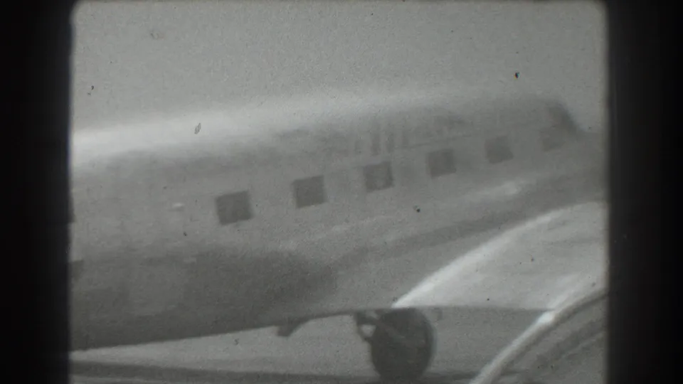 Soft, overexposed 1939 San Francisco frame showing the Mainliner aircraft side, passenger windows, wing, and engine housing on the tarmac.