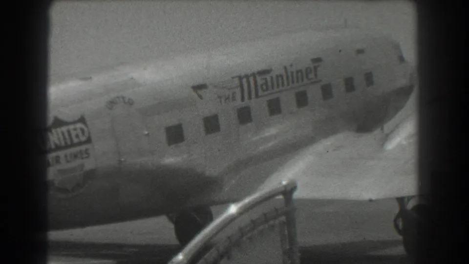1939 San Francisco airport footage showing a United Air Lines DC-3 Mainliner taxiing past a railing in black-and-white 8mm.