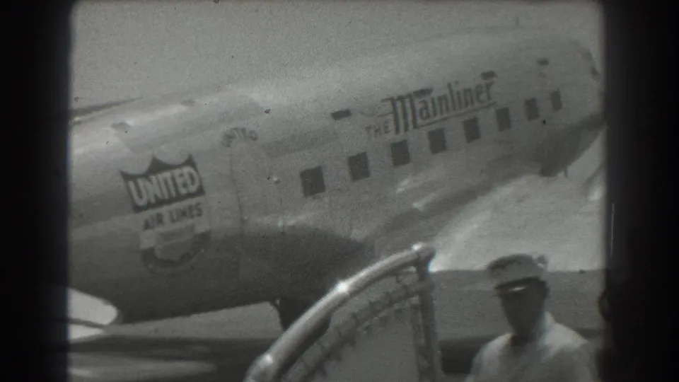 United Air Lines DC-3 Mainliner taxiing at a San Francisco airport, with airline logo, windows, railing, and a partly visible person.