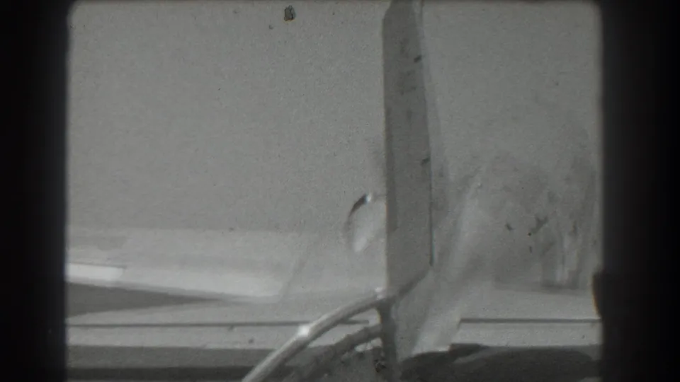 Black-and-white 8mm view of a 1939 San Francisco propeller aircraft tail with the propeller turning beside the wing.