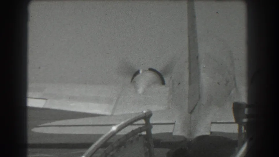 1939 San Francisco home-movie frame with the aircraft wing and tail passing through a low, close runway-side composition.