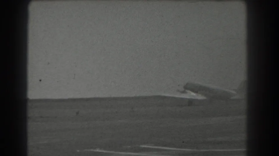 The aircraft continues along the runway or field, with its wing and tail visible against a hazy 1939 San Francisco sky.