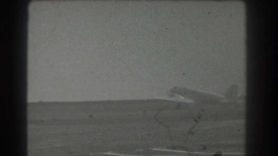 The aircraft reaches the right side of the 1939 San Francisco airfield frame, with runway foreground, haze, and visible film wear.