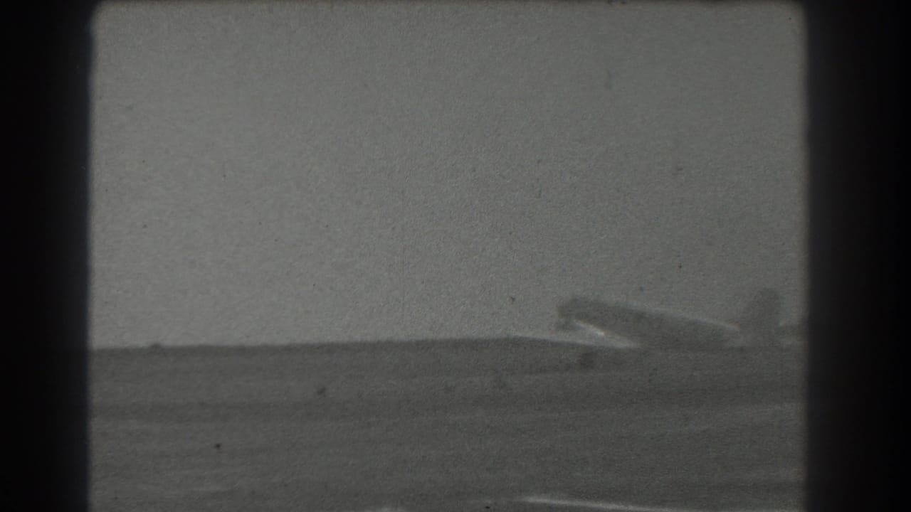 Light-colored propeller airplane on a distant runway under an open sky.