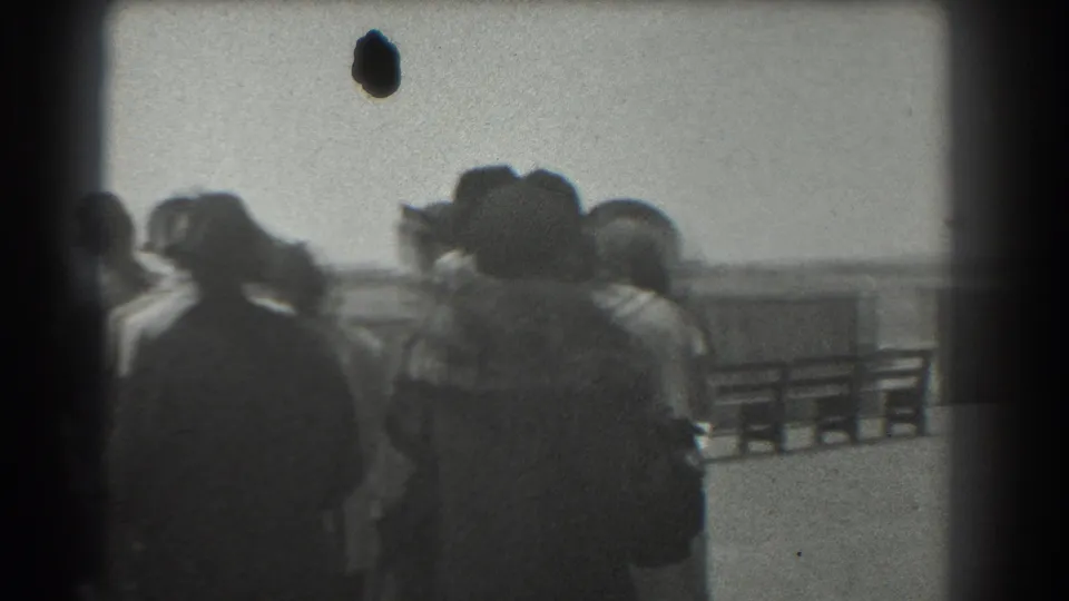 Candid 1939 San Francisco frame of several adults in coats and hats gathered at a public waterfront or boardwalk railing.