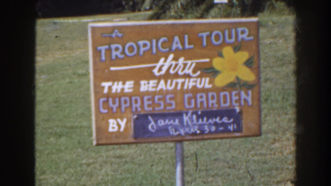 Hand-painted tropical tour sign standing in grass.