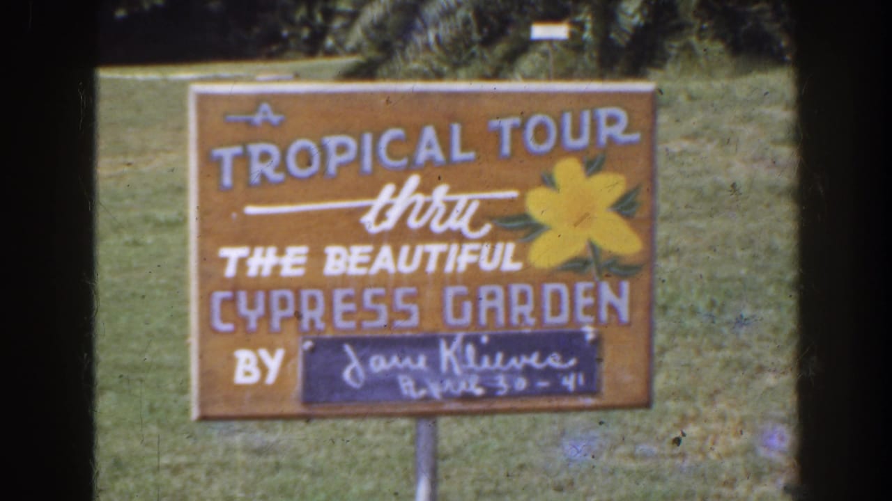 Tropical tour sign with flower artwork and handwritten lower panel.