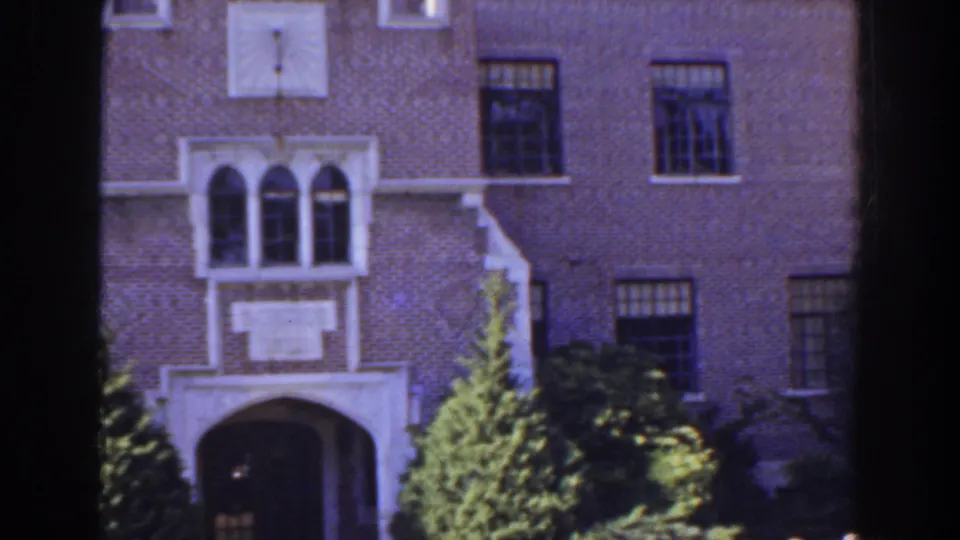 1941 Florida frame centered on a brick institutional-looking facade with white stone accents, arched entry, windows, and trees.