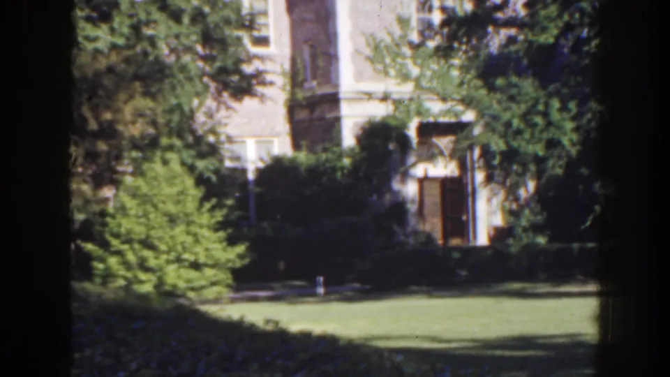 Static 1941 Florida exterior view of a possible church or large house seen through heavy garden foliage.