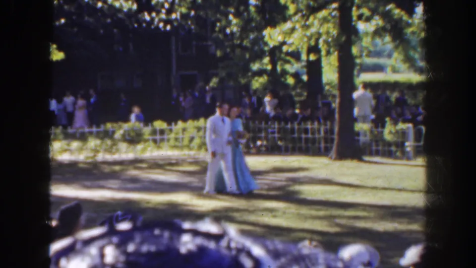 Near the end of the clip, the formally dressed couple walks across a shaded lawn with the white fence and Florida gathering behind them.