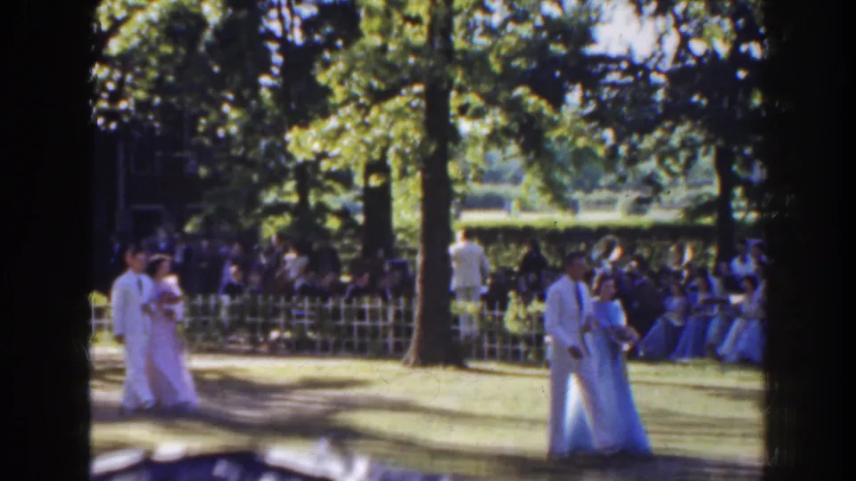 The 1941 Florida home movie shows the couple further along the garden lawn, framed by trees, fencing, and seated guests.
