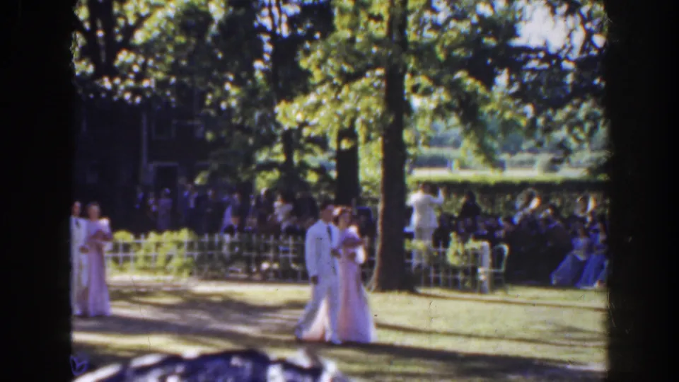 The couple continues along the grassy aisle at a Florida outdoor wedding, with bridesmaids and guests visible in the background.