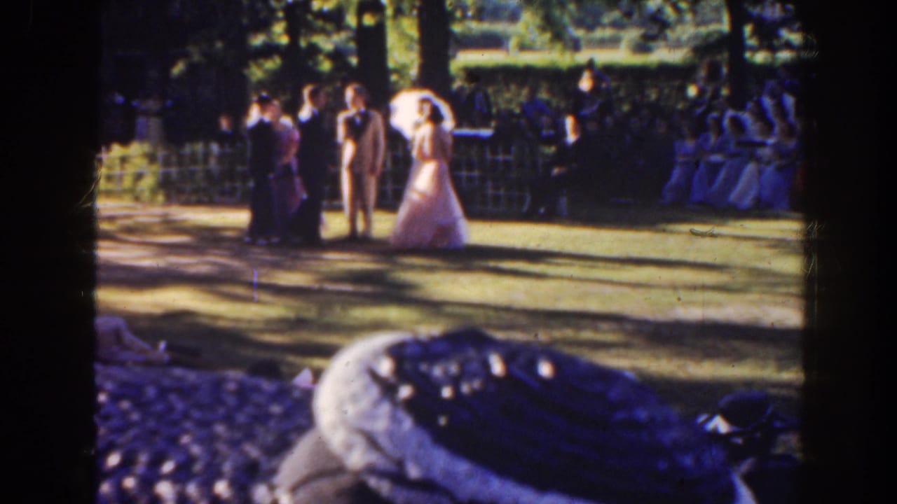 Bride and groom stand with young attendants on a lawn during an outdoor wedding.