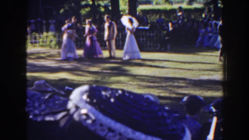 Final 1941 Florida wedding frame showing the bride, attendants, suited guests, and seated onlookers in a shaded outdoor setting.