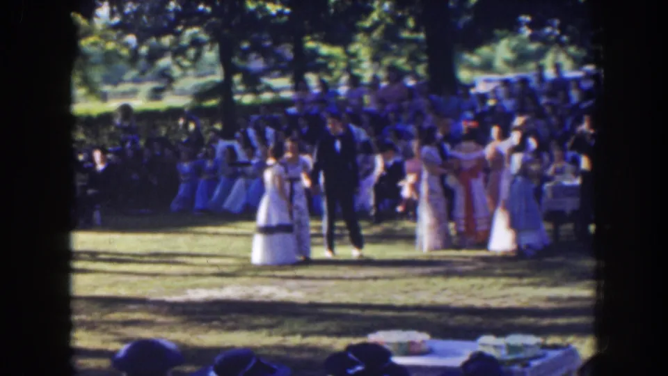 1941 Florida 8mm frame showing the bride, groom, and attendants before a seated audience during an outdoor wedding ceremony.
