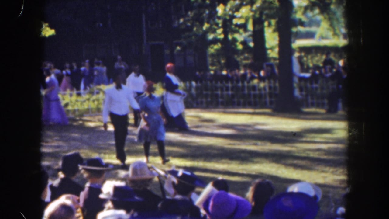 A man in a white shirt leads others across grass in front of spectators.