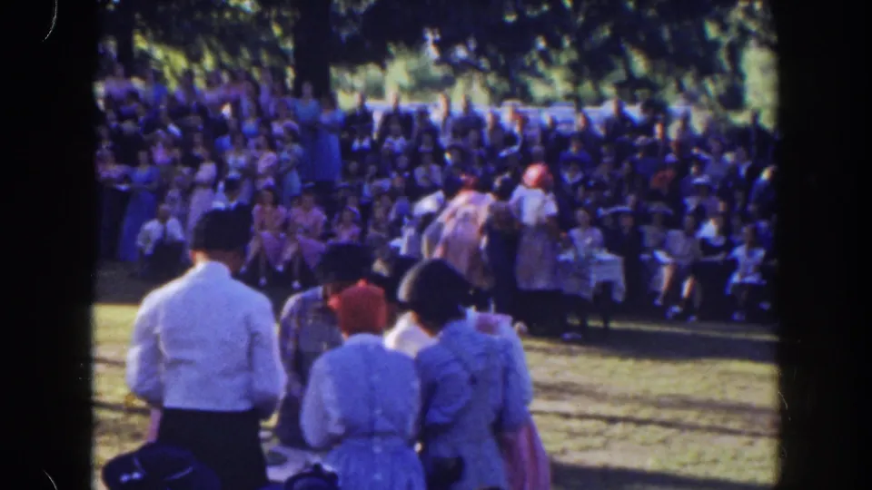 A small group stands on the lawn facing a large seated crowd during the 1941 Florida outdoor event, with a table visible at the side.