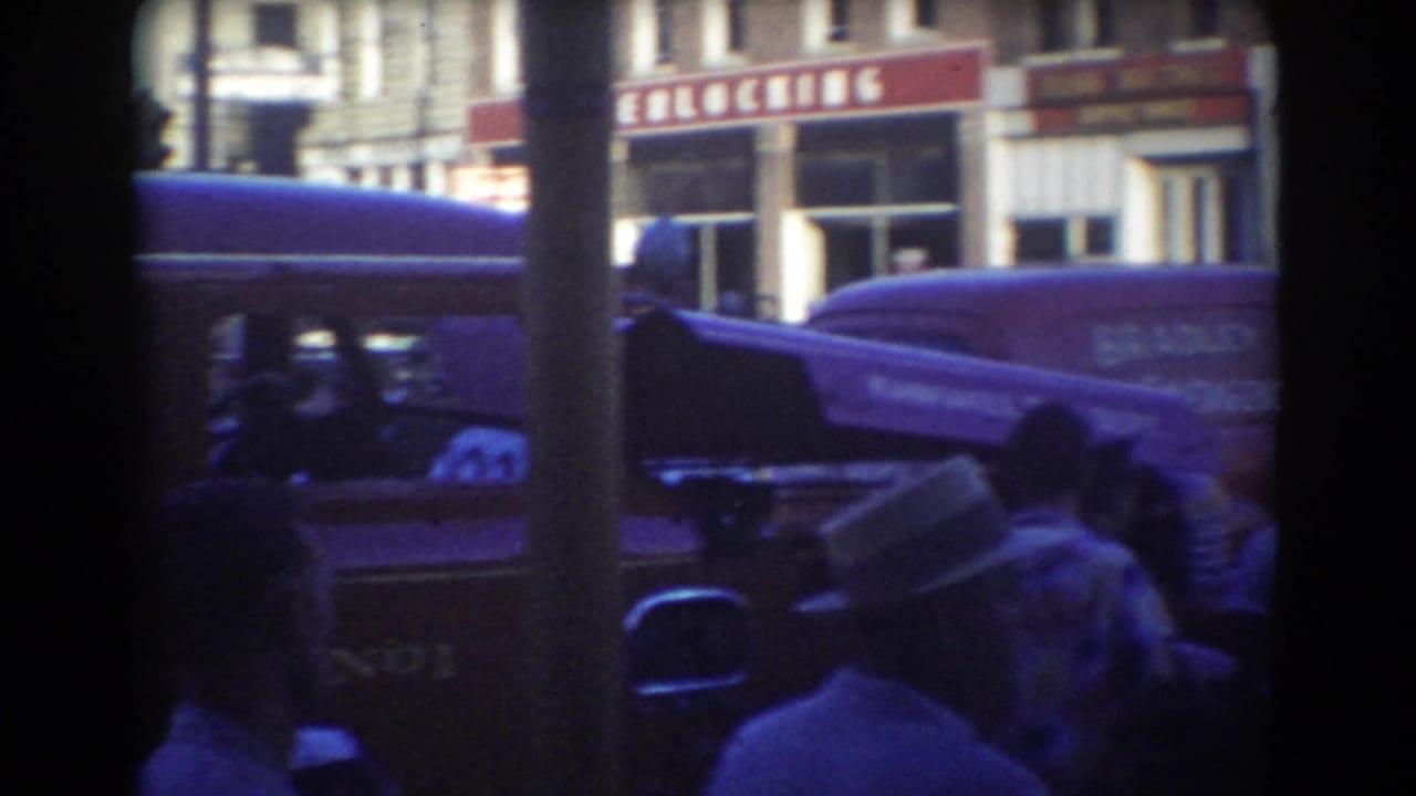 Crowd beside a fire department van and panel wagon on a downtown street.