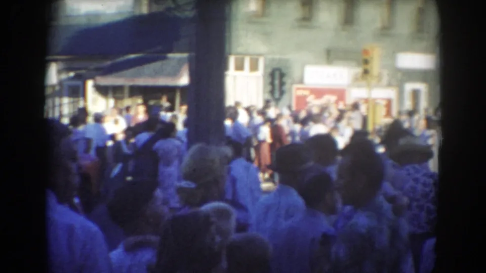 1958 York, Nebraska downtown crowd with storefronts, street signage, a Mobilgas sign, and people gathered in bright street light.
