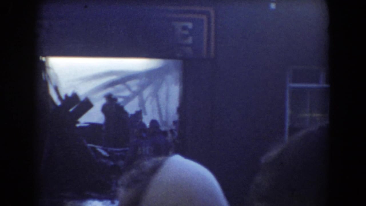 Spectators stand before a dark storefront and bright emergency scene.
