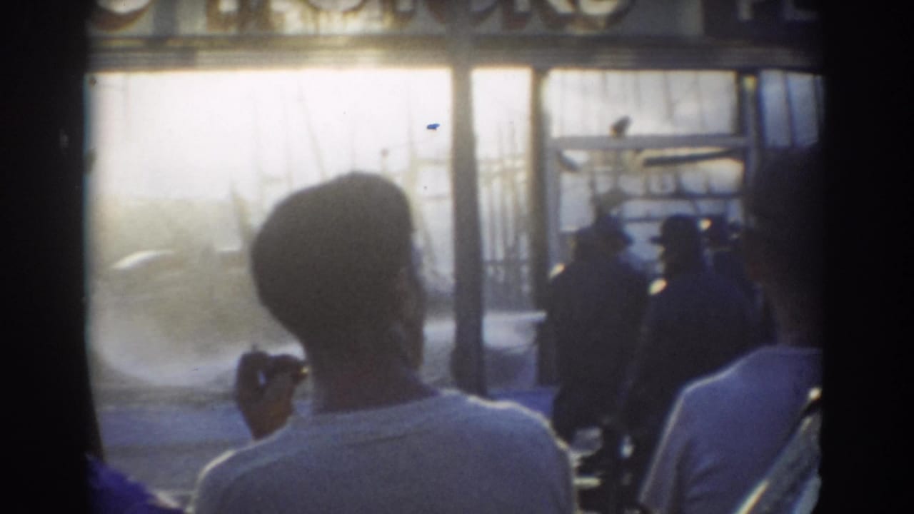 Spectators seen from behind watch water spray through a misty industrial opening.