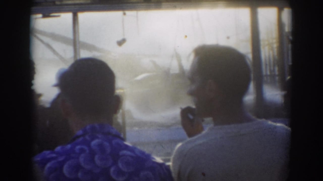 Two men seen from behind look toward mist and water spraying near metal framing.