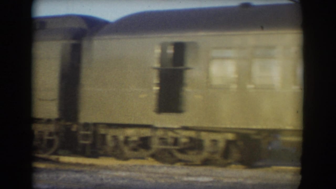 1958 York, Nebraska frame of a passing passenger-style rail car with windows, a dark doorway, roofline, wheels, and track below.