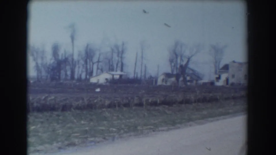 York, Nebraska home-movie frame from 1958 with a small distant house, open field, bare trees, and soft 8mm color.