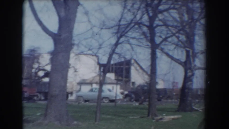 1958 York, Nebraska frame showing bare trees, grass, a light-colored car, and residential buildings beyond.