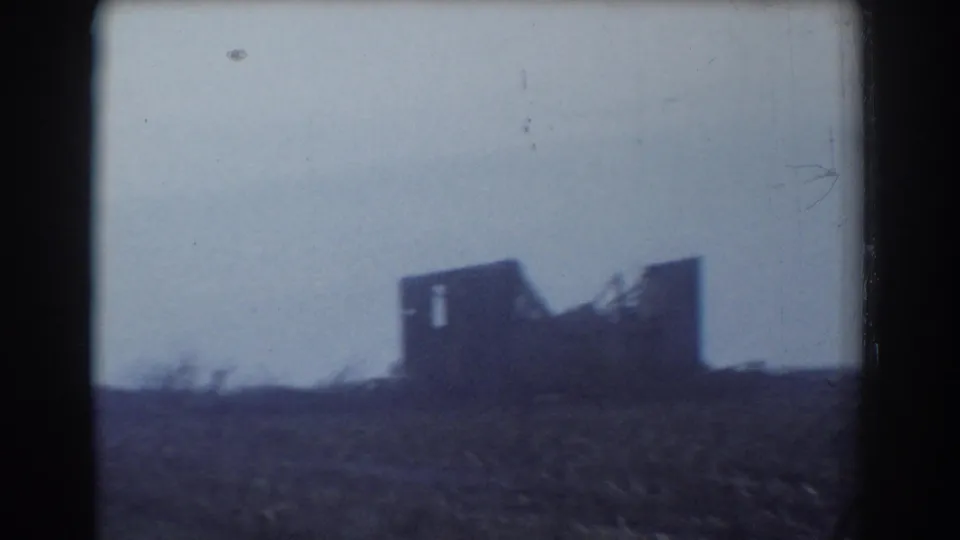 The damaged rural structure remains visible across the field, its broken roofline silhouetted against the pale sky in York, Nebraska footage.