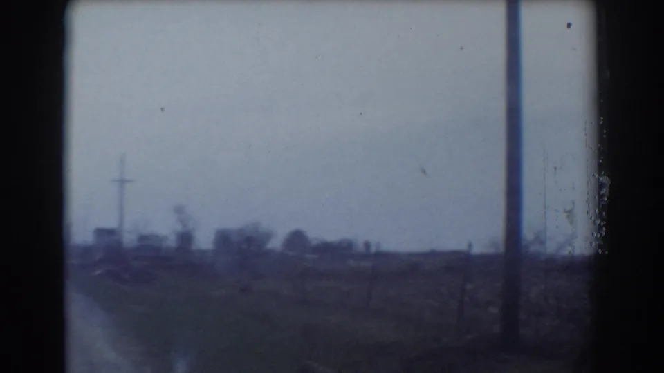 Passing 1958 York, Nebraska road view with a utility pole, open fields, and distant structures or trees.