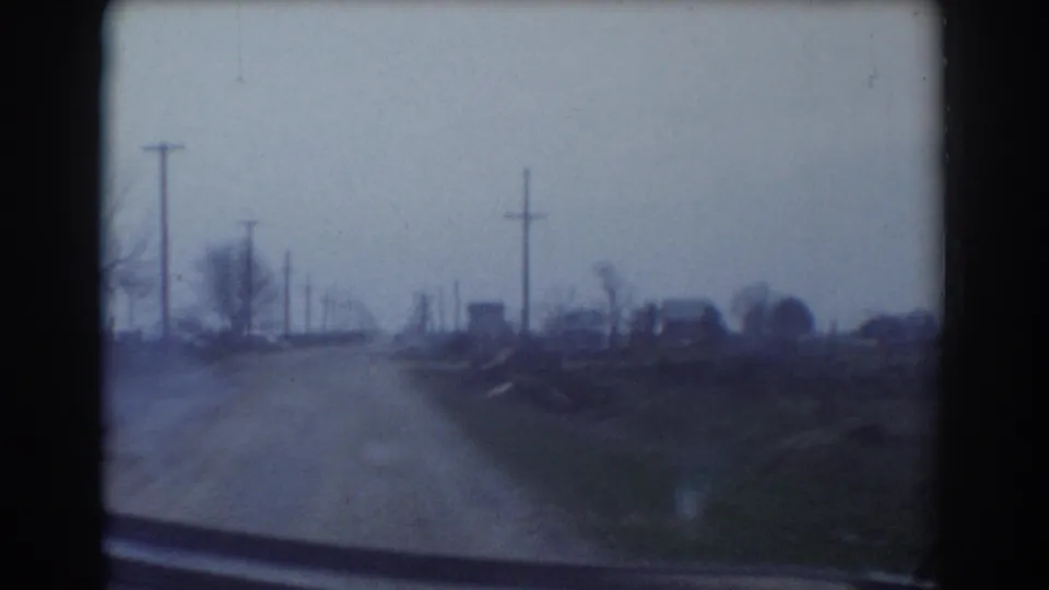 1958 York, Nebraska 8mm frame of a rural road receding between utility poles, fields, and sparse trees.