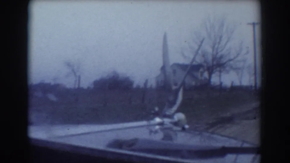 1958 rural York, Nebraska driving view with the car hood ornament, bare trees, utility pole, and a distant house near the road.