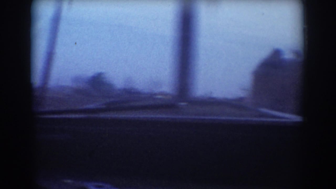 York, Nebraska 1958 home-movie frame looking through a moving car windshield toward a dim rural storm-damage scene.