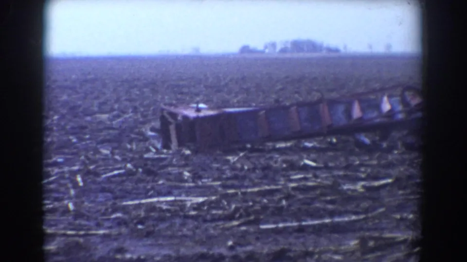 York, Nebraska farm-field aftermath frame with a large damaged debris section in the foreground and trees along the distant horizon.