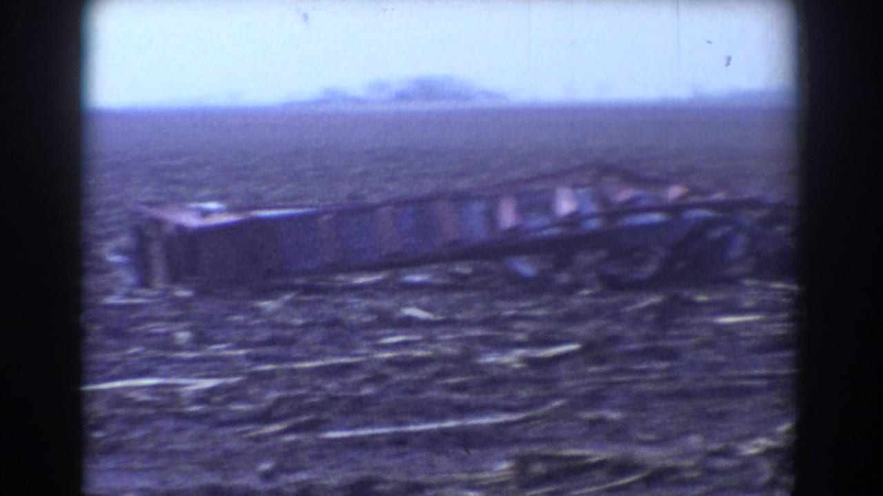 1958 York, Nebraska tornado aftermath showing open ground scattered with splintered debris and dark metal wreckage.