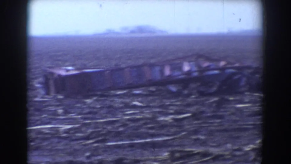 1958 York, Nebraska tornado aftermath showing open ground scattered with splintered debris and dark metal wreckage.