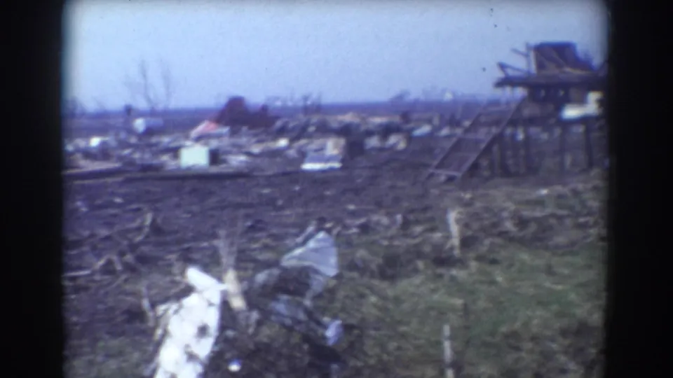 1958 York, Nebraska aftermath view with a damaged raised structure, bare trees, and debris spread across open ground.