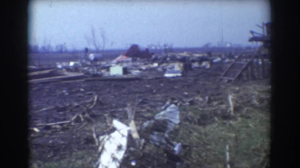 York, Nebraska tornado aftermath showing scattered rubble, bare trees, and part of a damaged structure at frame right.