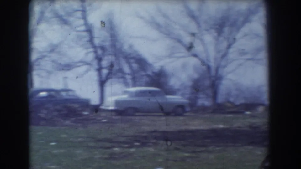 A parked 1950s sedan appears near bare trees and open grass in the York, Nebraska home-movie footage.
