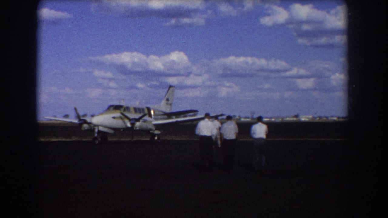 Men continue walking toward a small propeller plane parked on the runway.