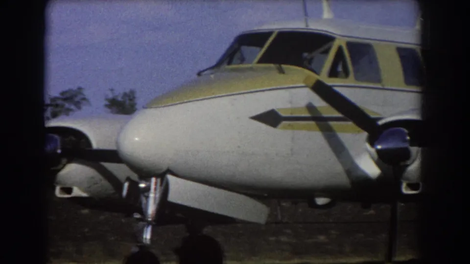 Final 1967 Brisbane frame shows the front section of the parked twin-engine airplane with cockpit glazing, propeller, and landing gear.