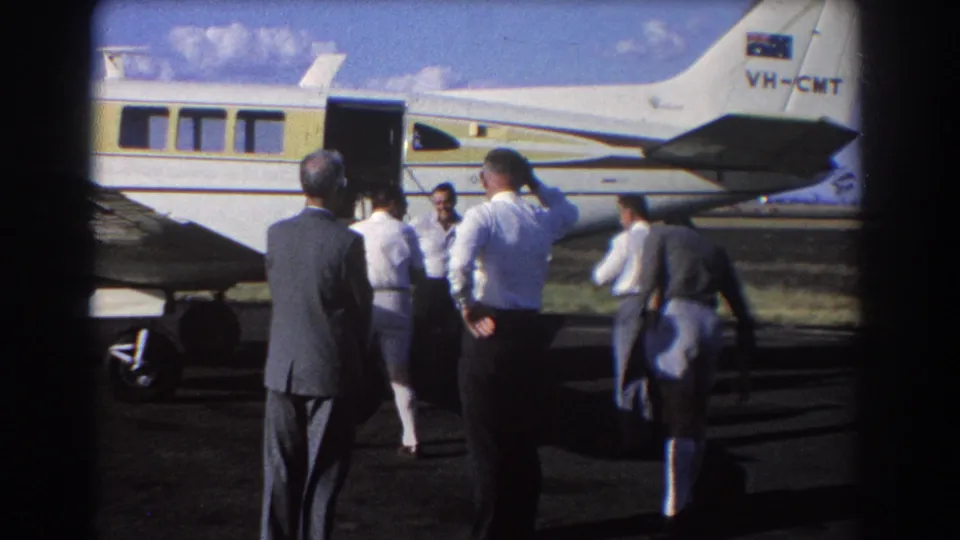 Businessmen and crew appear beside a small white and yellow aircraft marked VH-CMT at a Brisbane airfield in 1967.